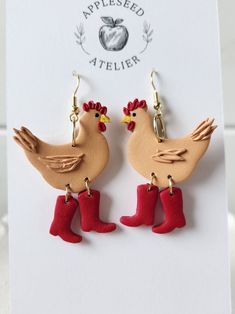 the earrings are made out of wood and have red rubber boots on them, with an apple in the background