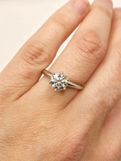 a woman's hand with a diamond ring on top of her finger, showing the center stone