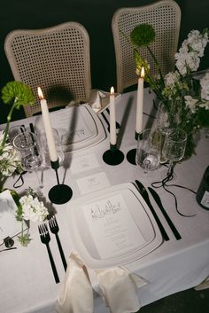 the table is set with white linens and black napkins, candles, and flowers