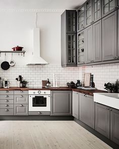 a kitchen with gray cabinets and wooden floors