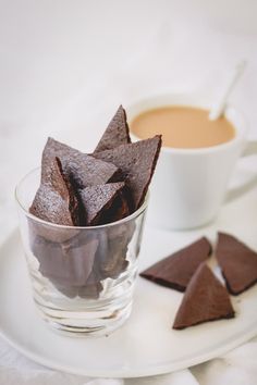 some chocolate chips are on a plate next to a cup of coffee and saucer