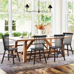 a dining room table with four chairs in front of it and a vase on top of the table