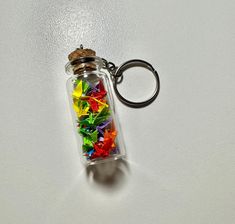 a glass bottle filled with lots of different colored paper stars on top of a white surface