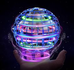 a hand holding a glowing ball in the dark with stars and lights on it's side