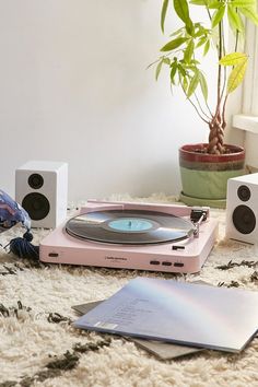 a record player sitting on top of a rug next to two speakers and a laptop