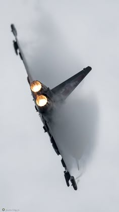 a fighter jet flying through the air with its lights on