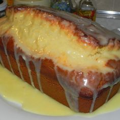 a loaf of pound cake covered in icing on a white plate with yellow glaze