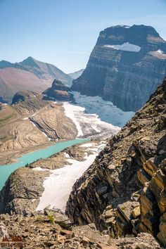 the mountains are covered in snow and ice as well as some blue lake below them