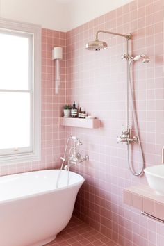 a bathtub and sink in a pink tiled bathroom