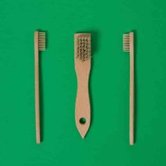 three wooden toothbrushes on a green background