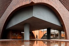 an entrance to a building with a person walking in the reflection on the ground below