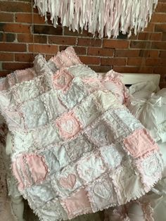 a pink and white quilt on top of a bed next to a brick wall