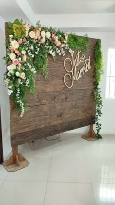 a wooden sign with flowers and greenery on it