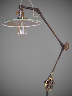 an old fashioned desk lamp with a glass shade on the top and one light attached to it