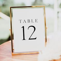 a table number sitting on top of a wooden table next to a white feathered object