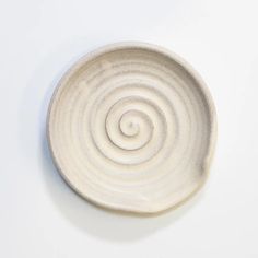 a white plate with a spiral design on the rim and bottom, against a white background