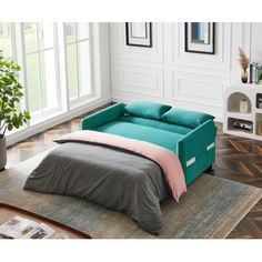 a bed sitting on top of a wooden floor next to a green plant in a living room