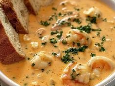 a bowl of soup with bread and shrimp in it on a tablecloth, ready to be eaten