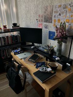 a wooden desk topped with a computer monitor next to a book shelf filled with books