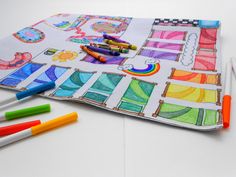 some crayons and markers are laying on top of a drawing book with different designs