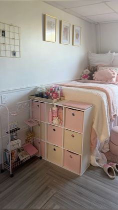 a bedroom with white walls and pink storage boxes on the floor next to a bed