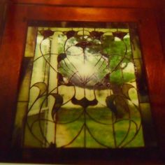 an old stained glass window with birds and flowers on it's sides in a wood frame