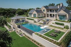 an aerial view of a large house with a pool in the foreground and landscaping around it