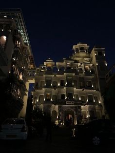 the building is lit up at night with lights on it's windows and balconies