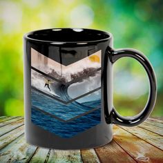 a black coffee mug sitting on top of a wooden table next to a green background