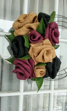 a wreath made out of burlock and fabric flowers on a window sill