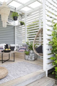 the porch is decorated with plants and hanging wicker chairs for seating on the deck