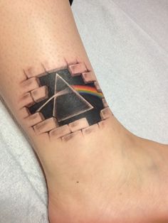 a pink floyd tattoo on the foot of a person with a dark side of the moon