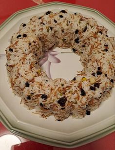 a white plate topped with a cake covered in rice and raisins next to a red table cloth