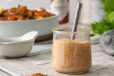 a jar filled with food sitting on top of a table next to a bowl and spoon