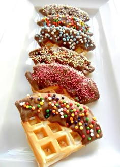 three waffles with chocolate frosting and sprinkles are on a white plate