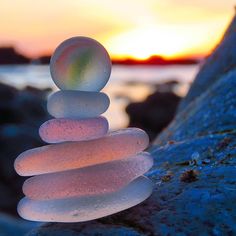 a stack of rocks sitting on top of a beach next to the ocean at sunset