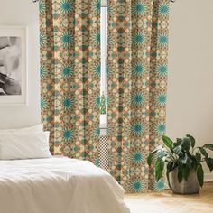 a white bed sitting next to a window with curtains on top of it and a potted plant in the corner