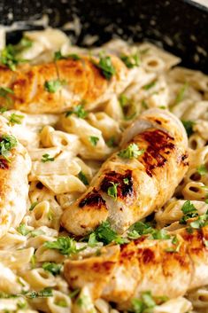 chicken and noodles in a skillet with parsley garnish on the side