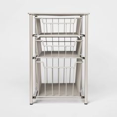 a white metal shelf with baskets on the top and bottom shelves, against a white background