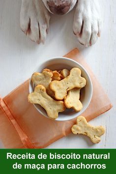 a dog with his paw in a bowl of cookies on top of a table next to an orange ribbon