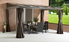 a patio covered in curtains next to a brick building