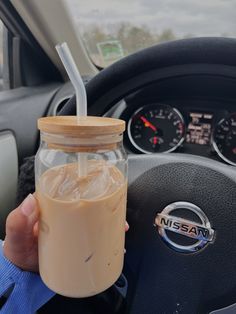 a person holding a drink in their hand and steering wheel behind the driver's seat