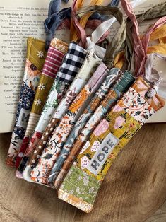 an open book sitting on top of a wooden table next to many different types of fabric