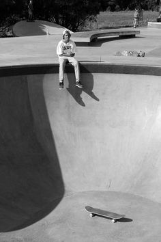 a skateboarder is sitting on the edge of a bowl at a skate park