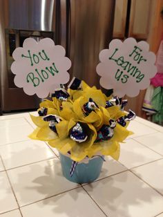 a vase filled with yellow flowers on top of a counter next to a sign that says you bloom