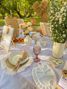 a table set up with plates and flowers in vases on top of the table