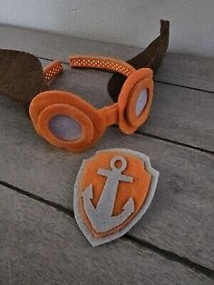 an orange and white pair of goggles sitting on top of a wooden table next to a sticker