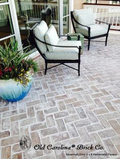 two chairs sitting on top of a patio next to a potted plant