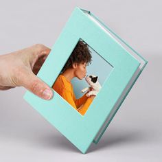 a person holding a small dog in front of a blue frame with a woman's face on it