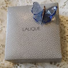 a blue butterfly brooch sitting on top of a silver box with the word la boutique written on it